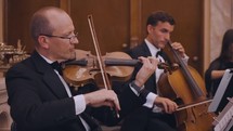 A stringed quartet plays music in a church - focused on the violinist.

