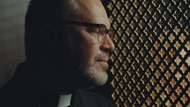 Female penitent and Catholic priest speaking though latticed opening of confessional booth in church. Rack focus shot
