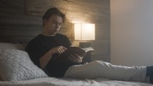 Young white male doing his own bible study and devotionals. He is in his bedroom relaxing, reading scripture and questioning his reading.