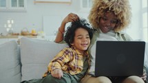 Happy Mother and Little Son Watching Cartoon on Laptop on Couch at Home
