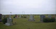 Graveyard tombstones in cemetery on cloudy day.