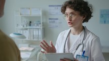 Female Doctor Using Tablet and Giving Consultation to Patient in Clinic
