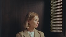 Beautiful mature woman sitting in confessional booth looking at side then posing at camera. Video portrait
