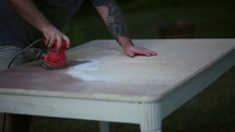 a man sanding a table 