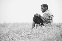 Boy reading bible in field