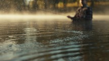 Young fly fisherman casting on a foggy river at sunrise