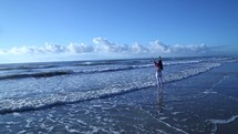 woman standing in the ocean with raised hands 