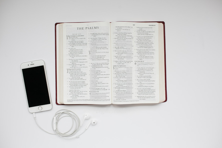 iPhone, earbuds, and open Bible 