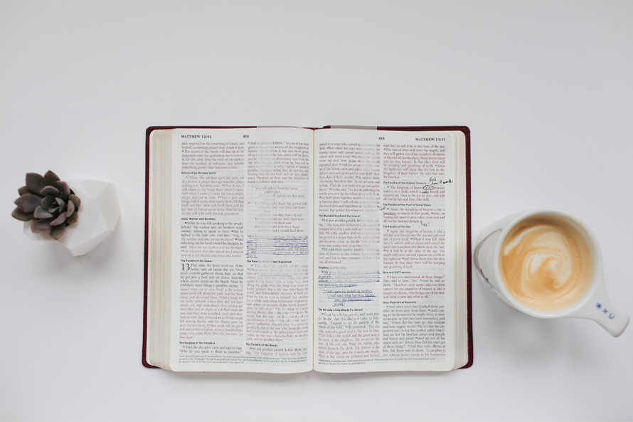 open Bible on a white background and a coffee mug 
