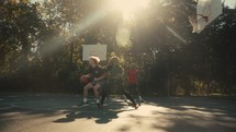 Young men playing basketball on an outdoor court on a sunny day