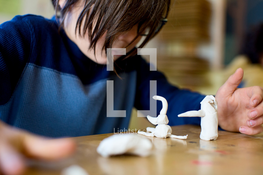 child working on clay figures at desk 