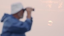 Old fisherman looking into the ocean using his binoculars