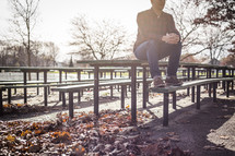 a man sitting on a picnic table in a park in fall 