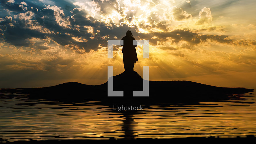 Silhouette of Jesus standing on a shore with water reflections and sun rays.
