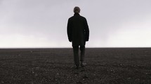 a man walking across a barren flat landscape 