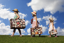 Three sisters holding vintage suitcases- for editorial use only