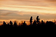group of people standing outdoor at sunset 