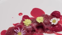 Presentation of a gourmet dish of tuna carpaccio with edible flowers
