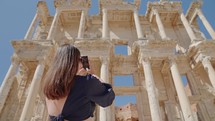 Female tourist visiting and taking pictures of Celsus Library in ancient city Ephesus, Anatolia in Selcuk, Turkey. Slow motion