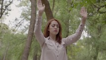 a woman with raised hands standing outdoors 