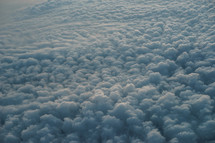 Photograph of a sky full of clouds from an airplane windows portraying the beautiful creation of God's heavens, which can be used as a decorative background or wallpaper for church services and bulletins.