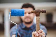 a man holding a paint roller and hammer 