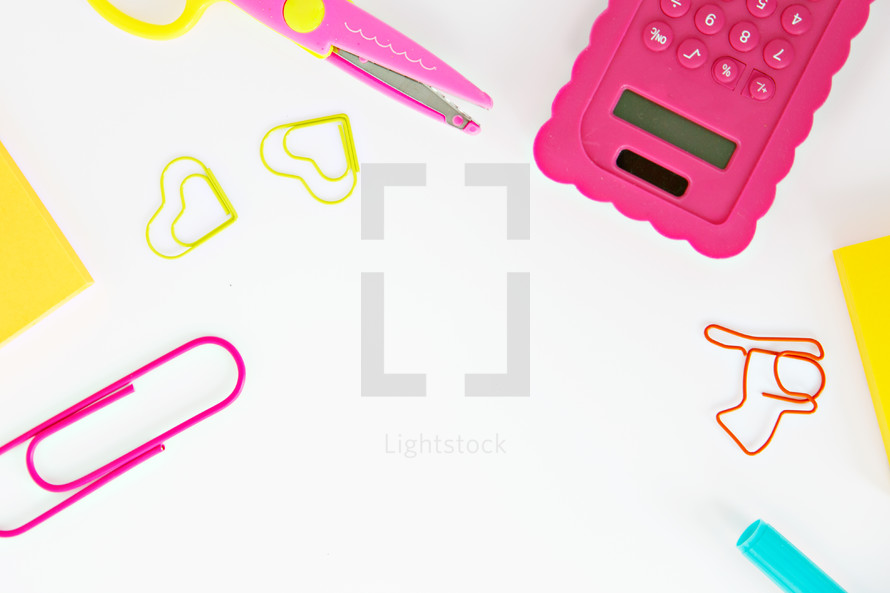 calculator, scissors, markers, and paperclips on a white background 