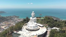 Parallax view of The Great Buddha of Phuket against the blue ocean landscape - Aerial wide Orbit panoramic shot