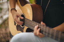a girl playing a guitar outdoors 