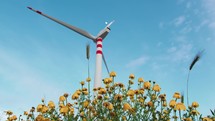 Wind power plant turbine for electric clean energy near a park of flowers at sunset