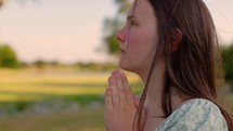 Girl Praying Outside at Sunset