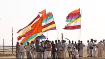 tribesmen holding colorful flags 