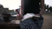 a woman writing in a journal on a beach 