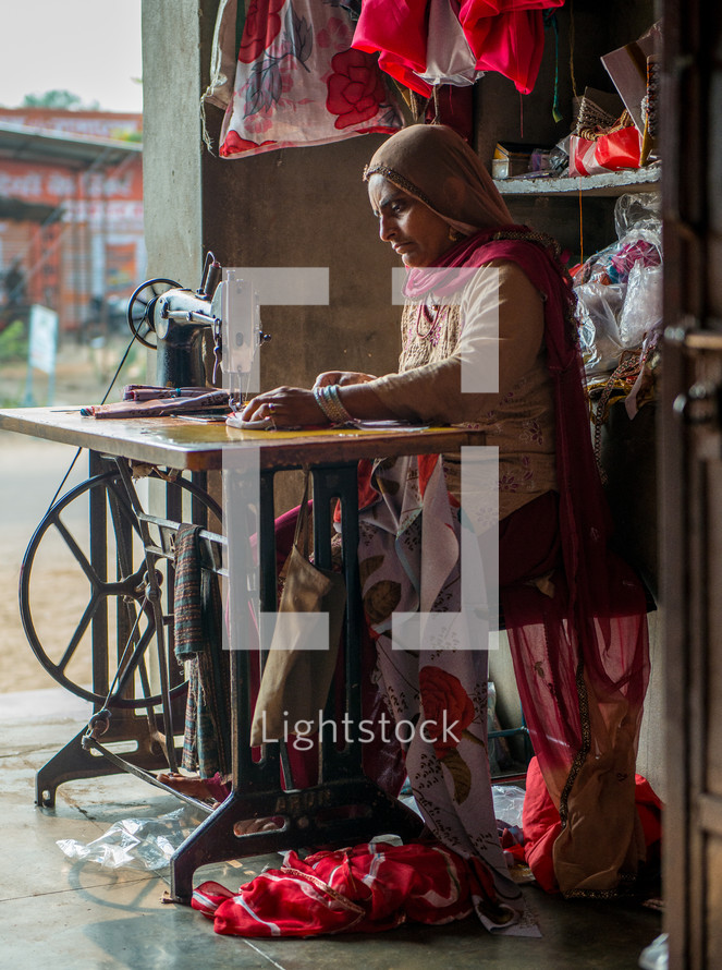 a woman in India sewing fabrics on a sewing machine 