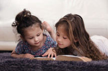 girls reading a Bible on the floor 