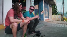 Guys sitting on a curb in Nepalees, enjoying a cold drink 