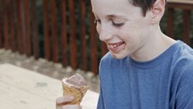 Young boy eating Ice Cream from a cone, enjoying and laughing
