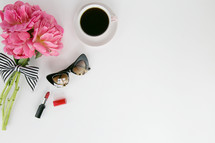 red lipstick, sunglasses, bouquet of flowers, and coffee cup on a white background 