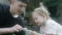 Father and daughter have tea party in the garden