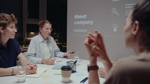 Woman Discussing Business Presentation with Team on Night Meeting
