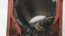 Industrial compost production site. Large rotary compost screening machine filtering compost. Slow motion