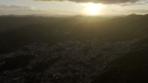 Drone flies left high over Ouro Preto, Brazil bathing in a rich sunset