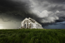Old School House Sits Under A Menacing Storm Cloud With Lush Green Grass
