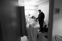 husband standing next to his wife in a hospital bed 