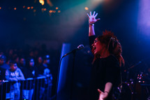 woman at a concert singing into a microphone 