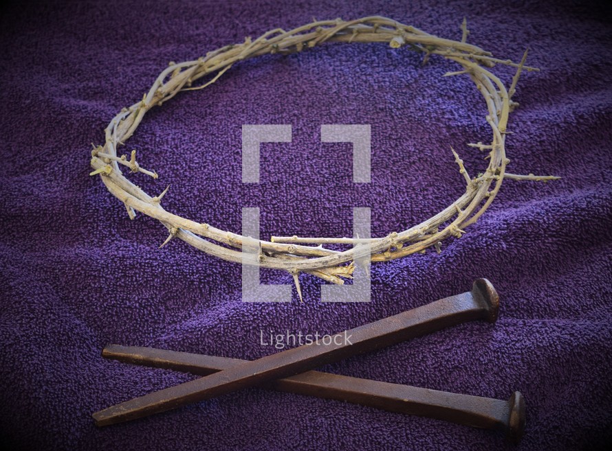 crown of thorns and two nails on a purple towel 