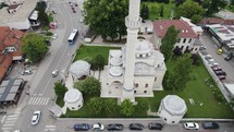 Aerial: Ferhadija mosque amidst urban Banja Luka streetscape. Tiltup to Skyline