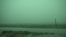 Heavy, dramatic, torrential downpour in severe thunderstorm. Rain drops, rainfall, in slow motion in rural, farmland area as rain waters green grass and crops after drought.