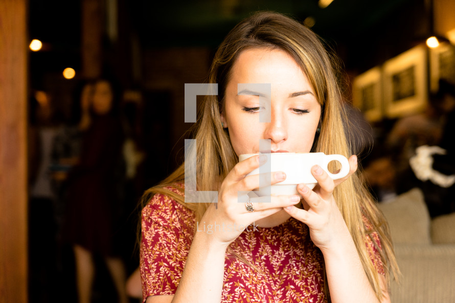 a woman sipping from a coffee cup 