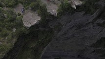 Drone orbits to the right with camera down over person on edge of cliff